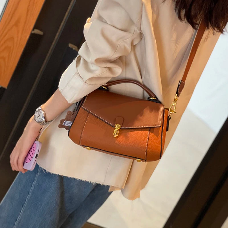 Leather crossbody bag worn on the shoulder with structured flap styling and long strap