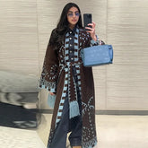 Mirror selfie showing a brown long knit cardigan with geometric pattern and tassel trim, belted at the waist over relaxed denim.