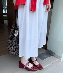 Side view of glossy red Mary Jane heels with buckle strap