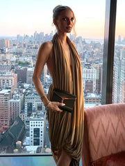 Side view of a ruched halter evening dress styled with a clutch