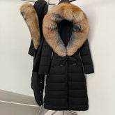Long black puffer coat on a hanger with oversized warm-toned fur-trim hood, belted waist, and sleek quilted panels.