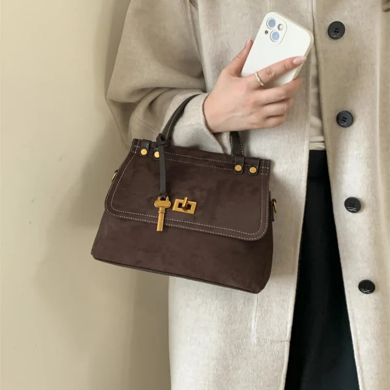 Brown faux suede top-handle saddle bag with gold hardware and flap closure