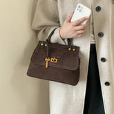 Brown faux suede top-handle saddle bag with gold hardware and flap closure