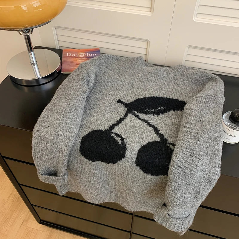 Gray sweater with black cherry motif folded for autumn style