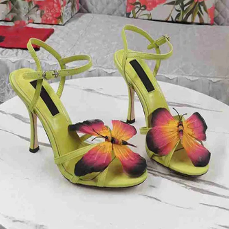 Green butterfly cross strap stiletto sandals styled for a summer party, with designs on a white surface.