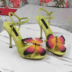 Green butterfly cross strap stiletto sandals styled for a summer party, with designs on a white surface.