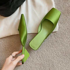 Pair of green slip-on women’s mules with wedge heel