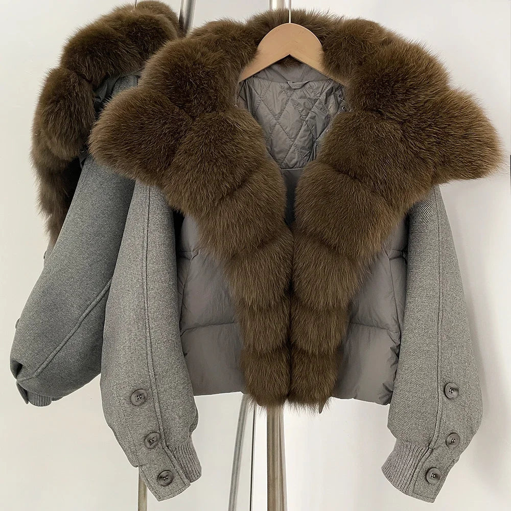 Grey cropped puffer jacket on a hanger with an oversized brown fur collar, showing a padded body and clean zip-front finish.