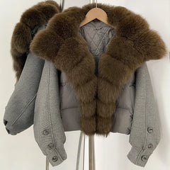 Grey cropped puffer jacket on a hanger with an oversized brown fur collar, showing a padded body and clean zip-front finish.