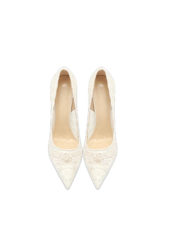 Pair of white lace high-heeled shoes on a light beige background