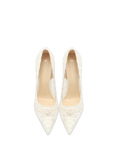 Pair of white lace high-heeled shoes on a light beige background