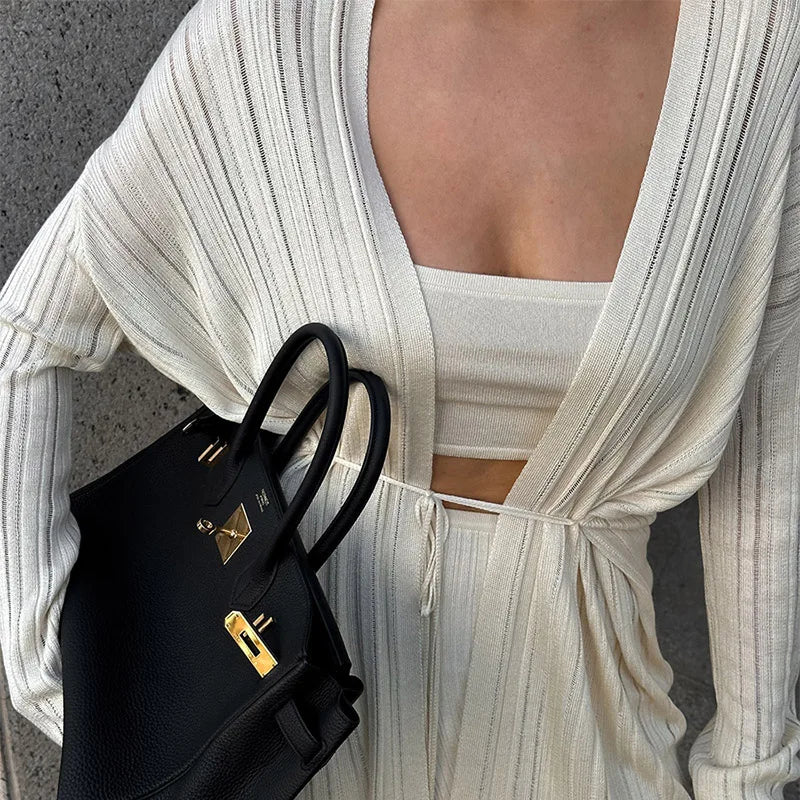 Person wearing a high street autumn knitwear juniors set in solid pattern holding a black handbag with a gold clasp.