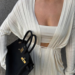 Person wearing a high street autumn knitwear juniors set in solid pattern holding a black handbag with a gold clasp.