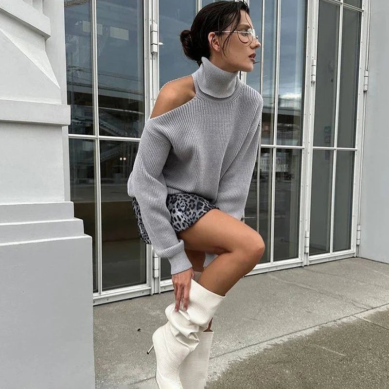 Person wearing a high street gray autumn casual sweater for women’s daily looks white knee-high boots, and patterned shorts outdoors.