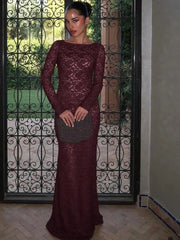 Woman in a burgundy lace dress standing in front of an ornate metal gate.