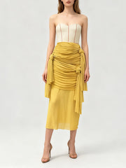 Front view of a yellow sculptural midi skirt with layered folds.