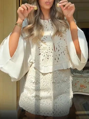 A woman wearing a matching set with intricate appliqué and an A-line mini skirt indoors.