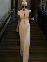 Model wearing an ivory beaded turtleneck sheath evening dress on stairs