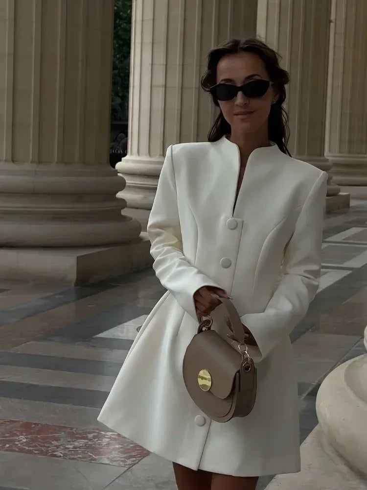 Outfit shot of an ivory long sleeve mini dress with a clean high neck and button front, styled for an elegant daytime event.