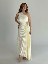 Model in an ivory one-shoulder pleated maxi dress with a waist cutout, standing in heels against a clean studio backdrop