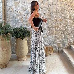 Woman in a junior A-line polka dot evening dress perfect for high street fashion holding a clutch in front of a stone wall.