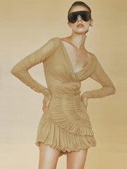 Woman wearing a khaki mesh-pleated bodycon mini dress with long sleeves and sunglasses on a beige background