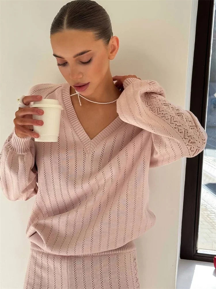 Woman wearing a ribbed knit pullover top with dropped shoulder holding a white cup.