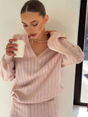 Woman wearing a ribbed knit pullover top with dropped shoulder holding a white cup.