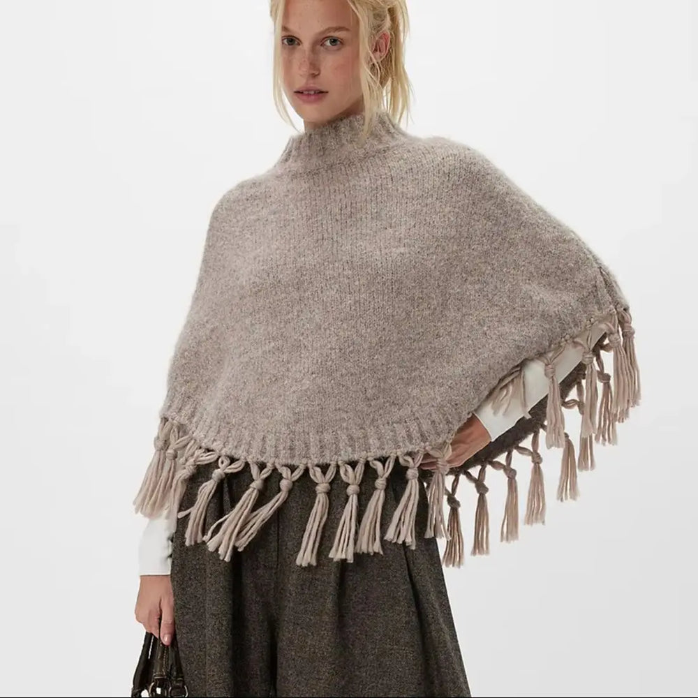 Fabric close-up revealing the knit texture and smooth blend used in the poncho construction.