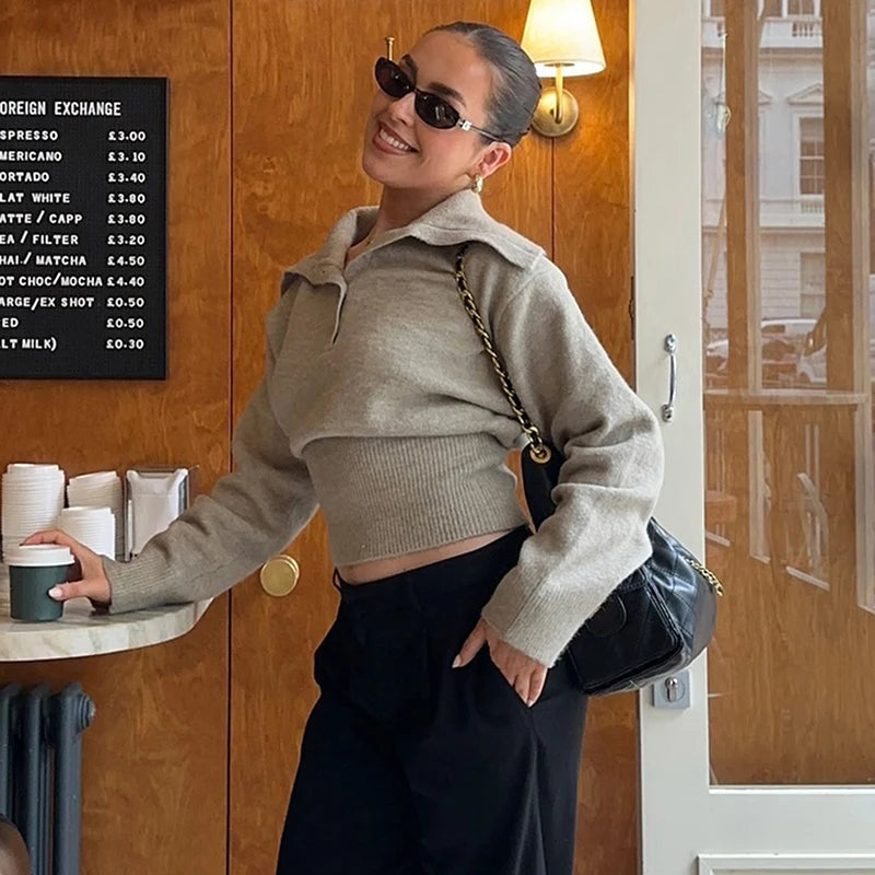 Woman wearing knitted polo pullover styled with tailored trousers on a city street