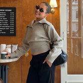 Woman wearing knitted polo pullover styled with tailored trousers on a city street