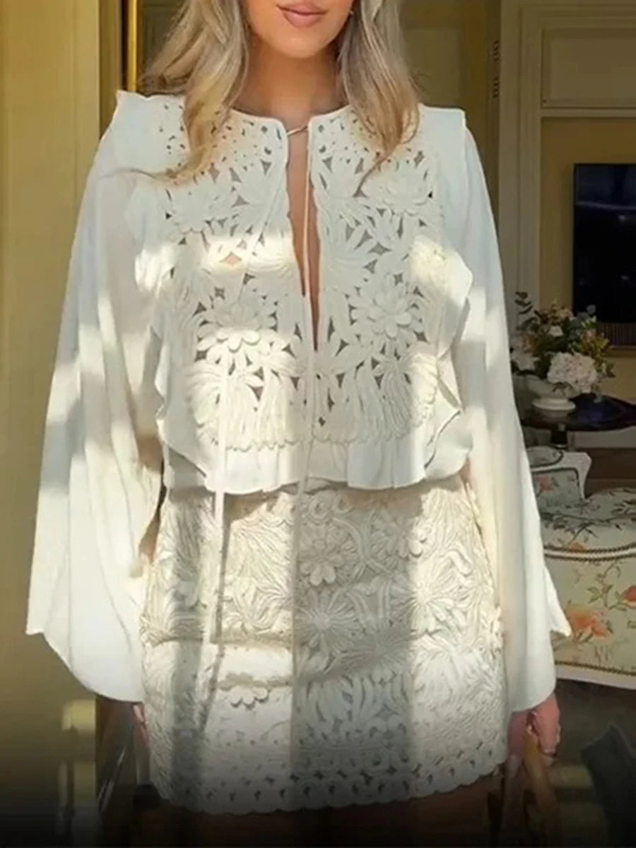 Person wearing a lace appliqué two-piece set with flare sleeve top and mini skirt in an indoor setting