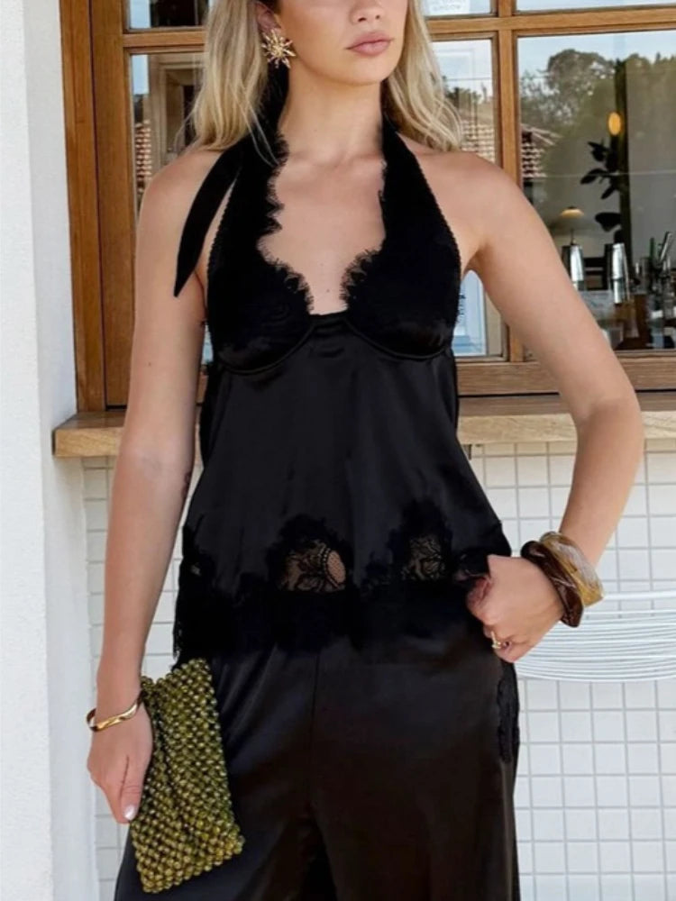 Model wearing a black lace halter vest top styled with tailored trousers, highlighting the clean neckline and fluid drape indoors.