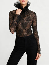 Sheer lace high-neck top with ruffled collar and slim sleeves styled against a white background for an elegant, textured look.