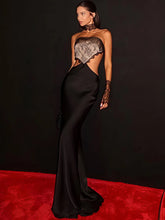Strapless lace and satin maxi dress with side cut-outs shown in an elegant evening setting on a red carpet.