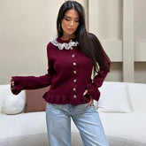Woman wearing a burgundy lace-trim knit cardigan with soft ruffle hem in a living room