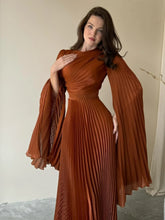 A woman wearing a lace-up batwing maxi dress in a chic, modern style.