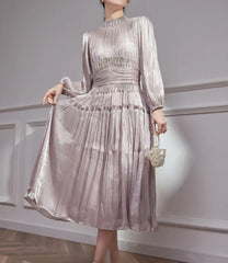 Side-angled view highlighting the airy pleats and soft lantern sleeve volume, with the midi hem falling at mid-calf in a studio setting.