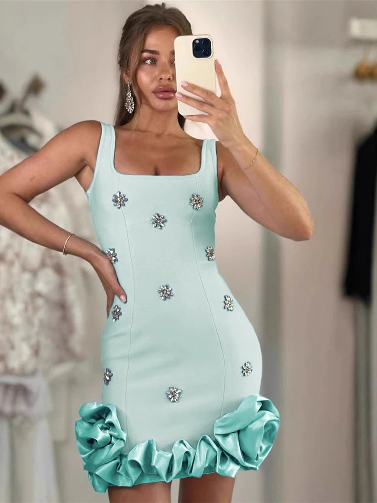 A woman taking a mirror selfie wearing a light blue crystal flower bandage mini dress styled for evening parties.