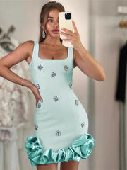 A woman taking a mirror selfie wearing a light blue crystal flower bandage mini dress styled for evening parties.