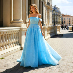 Model wearing a light blue off-shoulder tulle A-line gown with a side slit on a city street