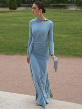 Woman in a Light blue ruched long-sleeve maxi dress styled for an autumn party, standing outdoors on a path with grass and trees in the background.