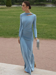 Woman in a Light blue ruched long-sleeve maxi dress styled for an autumn party, standing outdoors on a path with grass and trees in the background.