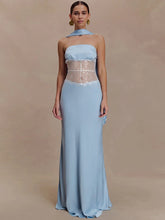 Model wearing a light blue strapless maxi dress with a scarf-style neck detail and sheer lace waist panel against a warm beige backdrop.