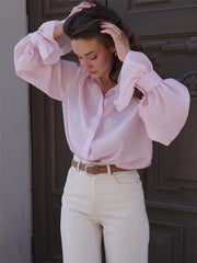 Woman wearing a light pink puff-sleeve blouse styled with white pants