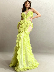 Model in a lime green floor-length gown with cascading ruffles and crystal detailing, posing in a studio against a neutral backdrop.