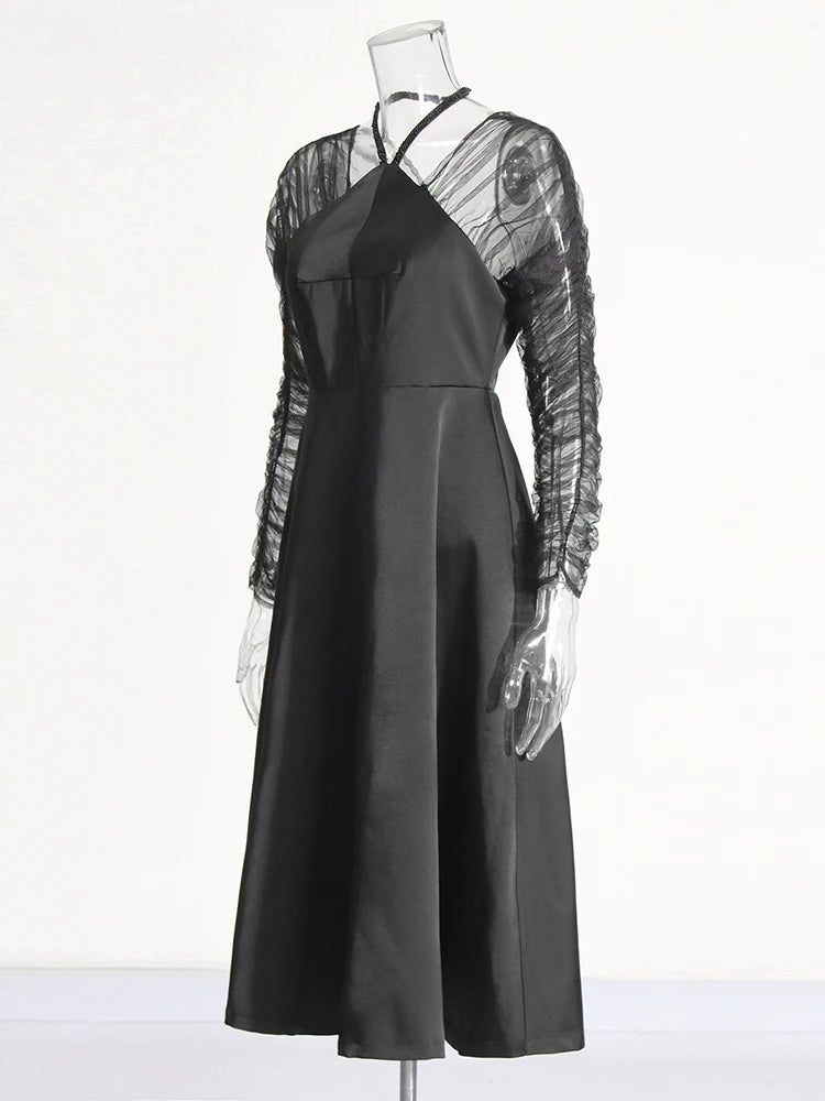 Black dress with sheer sleeves on a mannequin against a white background