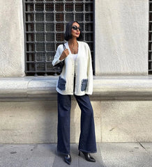Full outfit shot of a cream button-front cardigan with denim pockets, worn over a light tank with sunglasses and a structured black bag.