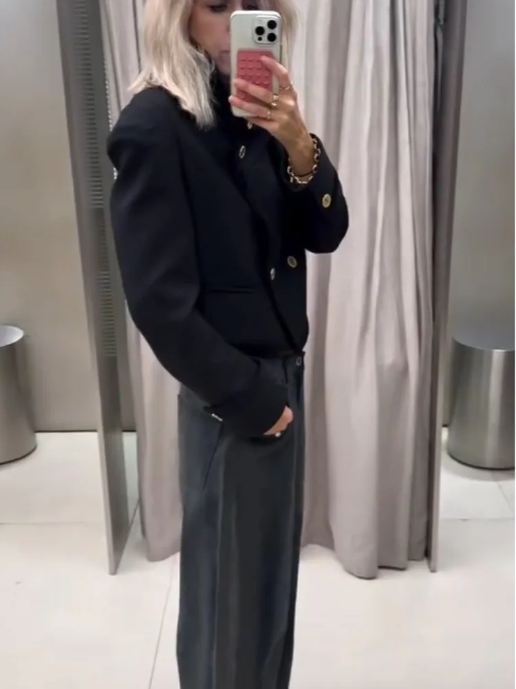 Outfit shot of a black stand collar cropped jacket worn with jeans, showing the tailored waist-length cut and long sleeves.