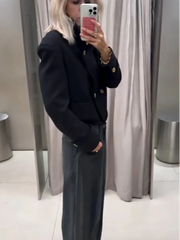 Outfit shot of a black stand collar cropped jacket worn with jeans, showing the tailored waist-length cut and long sleeves.